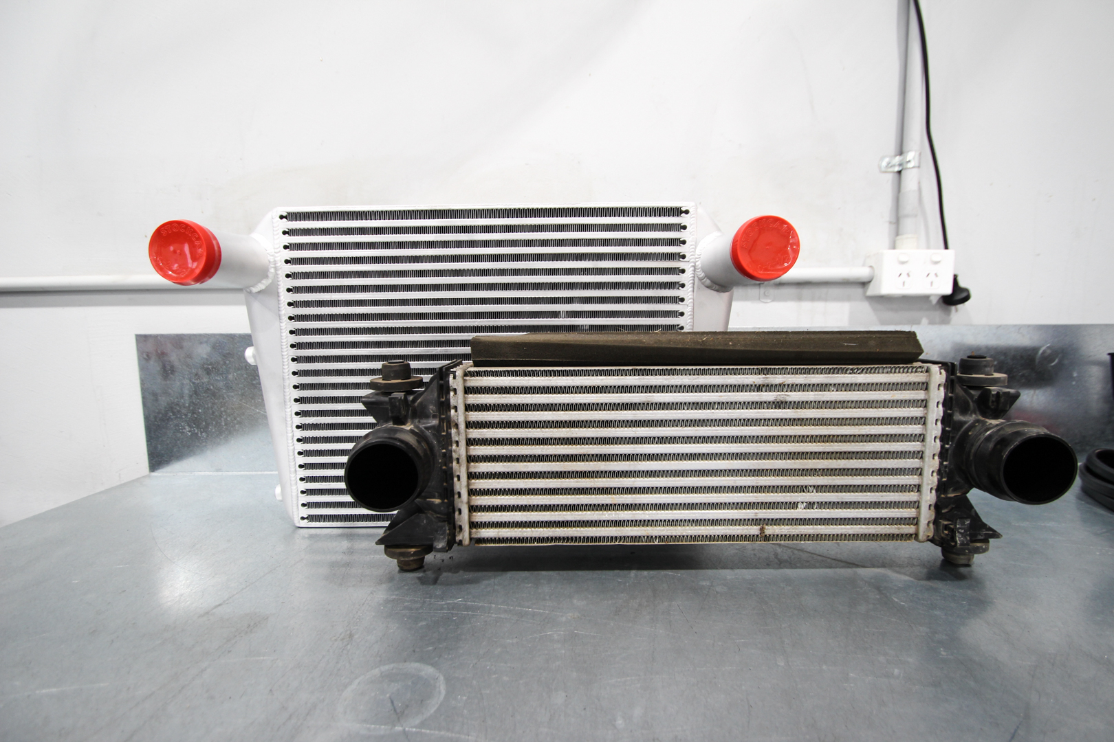 Factory Next Gen Ranger intercooler next to the larger HPD bar-and-plate intercooler